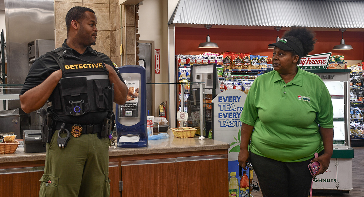 Askew talks to “Cousin Ruth,” an employee at a Royal Farms, in front of the checkout counter at the store.