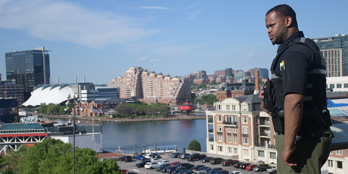 Brian Askew, in uniform, stands on the edge of Federal Hill Park, looking out over onto the Baltimore City landscape.