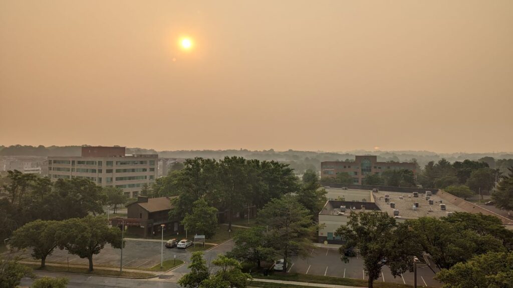 A photo captures the wildfire haze covering an area of Greenbelt, Maryland, with buildings in the forefront. The background of the image is difficult to make out due to the haze.